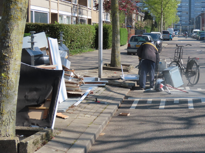 912675 Afbeelding van een man die oud metaal haalt uit een stapel grofvuil bij de ondergrondse afvalcontainers op de ...